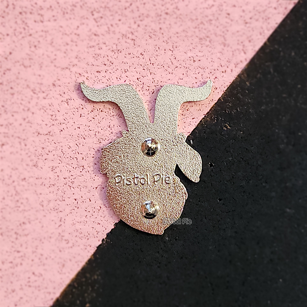 photo of the back of a goat shaped silver enamel pin with pistol pie logo embedded into the back