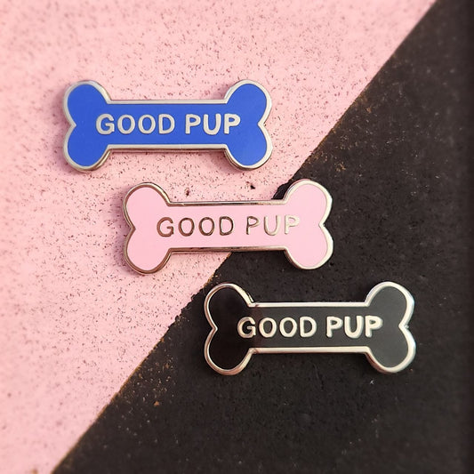 Three 'GOOD PUP' bone-shaped pins on a pink and black background