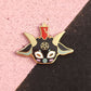 Colorful mask-like pin with horns on a pink and black background