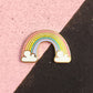Rainbow-shaped pin with clouds on a pink and black background