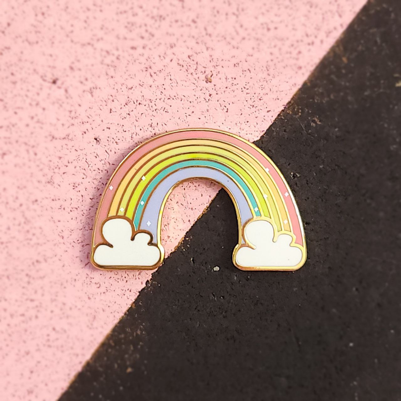 Rainbow-shaped pin with clouds on a pink and black background