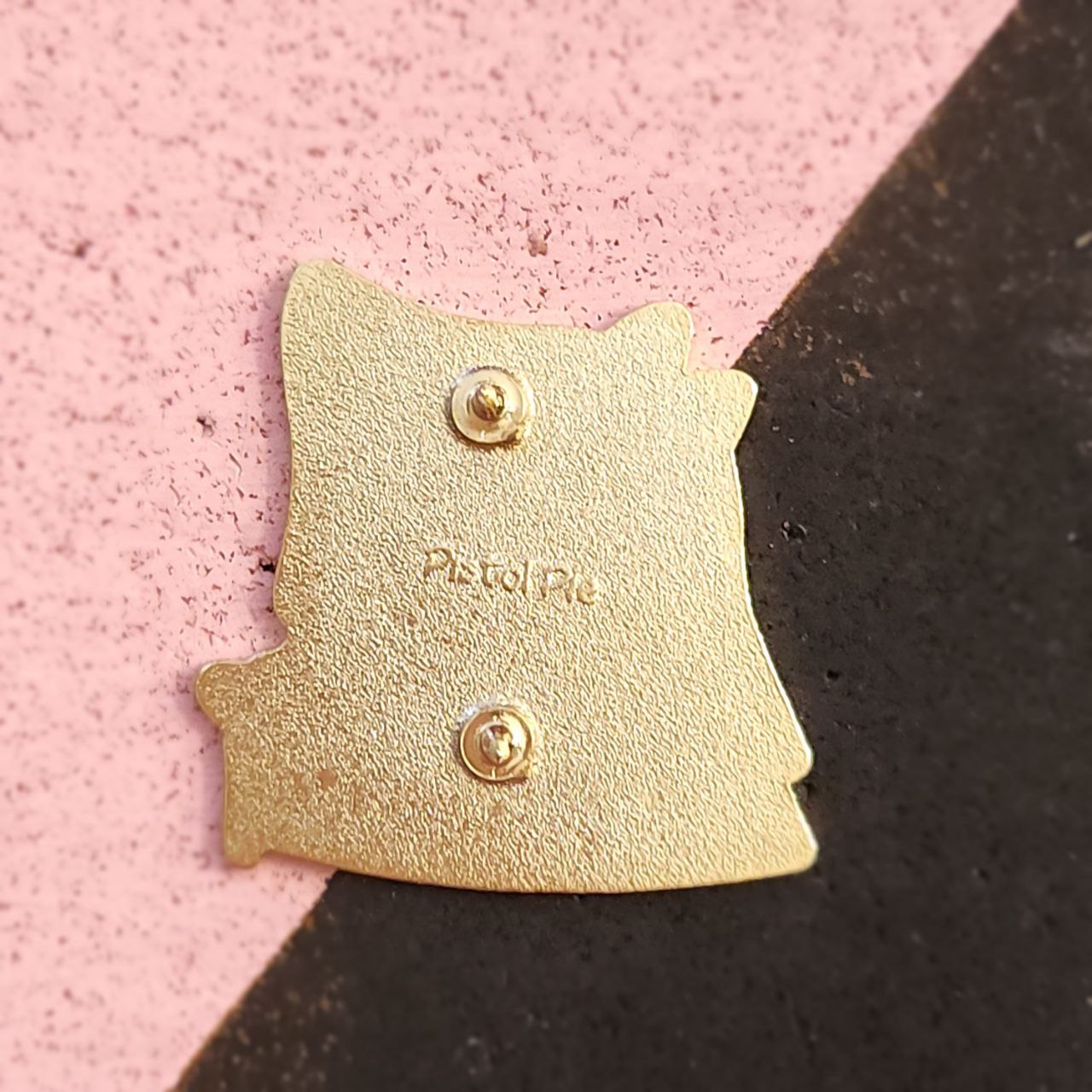 Gold pin on a pink and black background