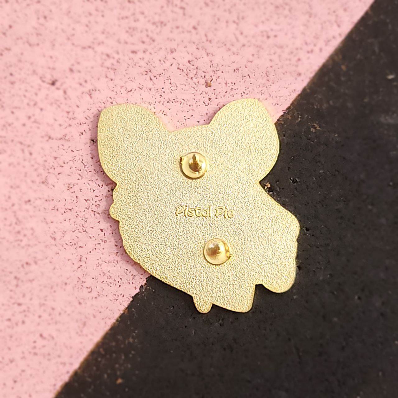 Gold pin on a pink and black background