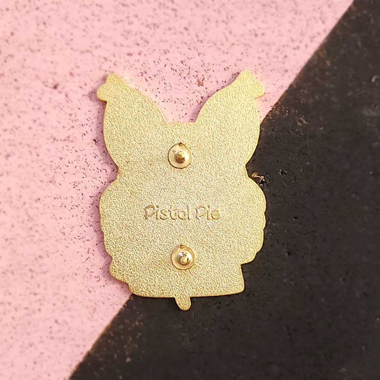 Gold pin on a pink and black background