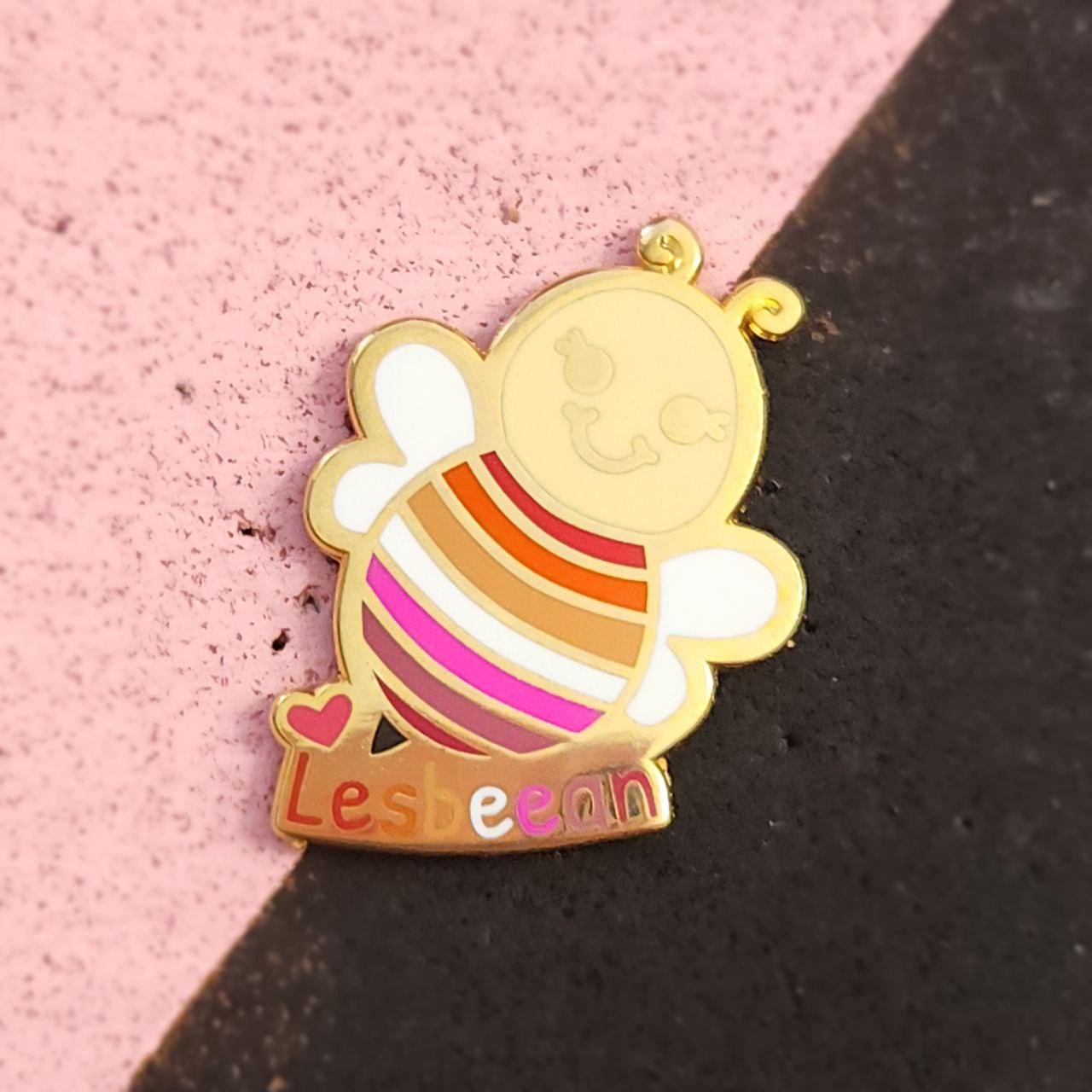 Colorful enamel pin with 'Lesbean' branding on a pink and black background