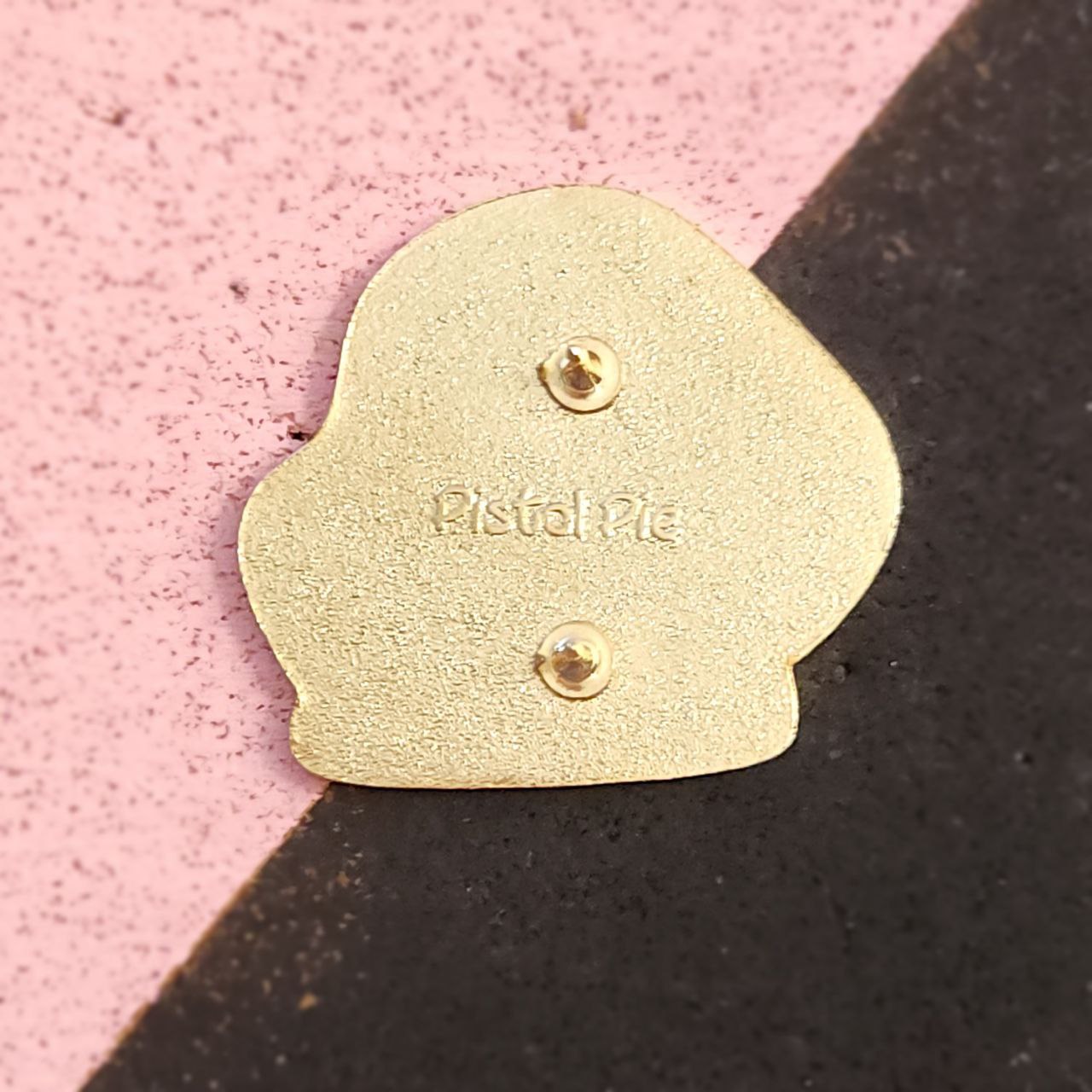 Gold pinon a pink and black background